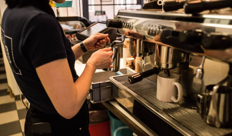 Eine Studentin brüht einen Kaffee in einem Gastronomiebetrieb auf