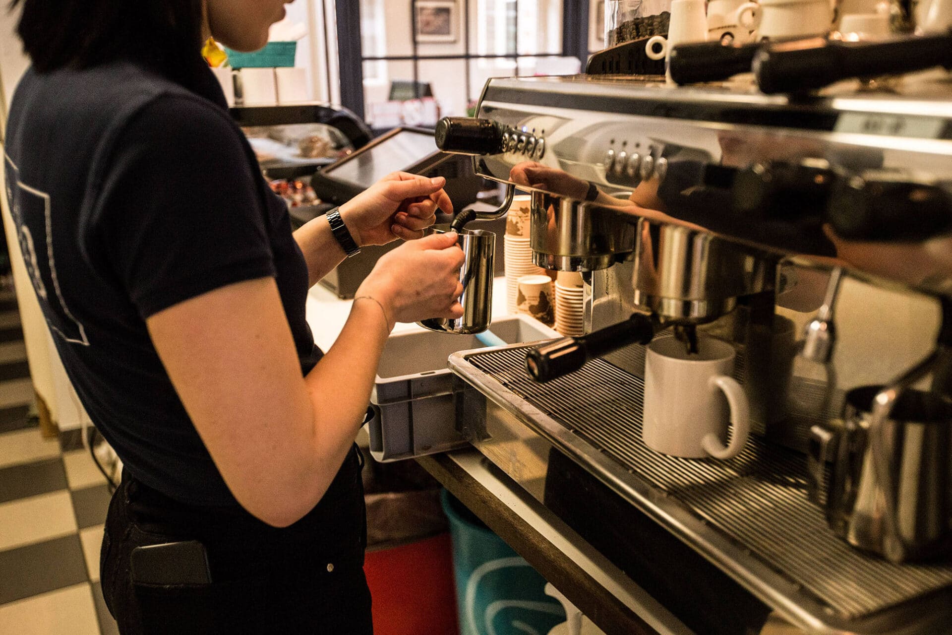 Eine Studentin brüht einen Kaffee in einem Gastronomiebetrieb auf