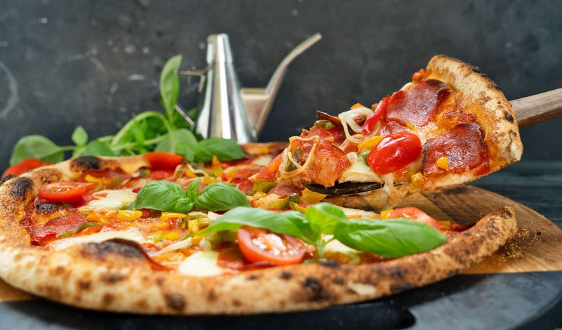 Eine Pizza mit frischen Tomaten und Basilikumblättern.