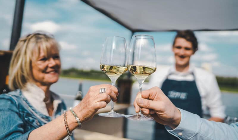 Zwei Gläser Weißwein, mit denen angestoßen wird.