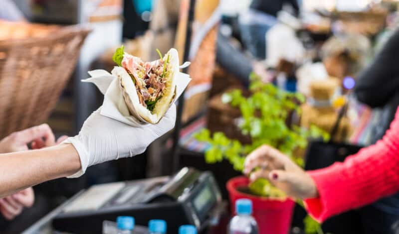 Koch reicht einem Besucher auf einem Streetfood-Markt eine Tortilla