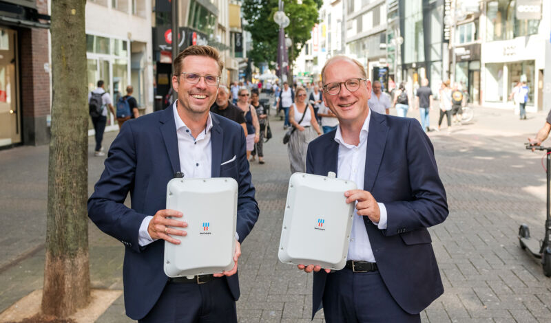 Das Bild zeigt Andree Haack und Timo von Lepel mit zwei WLAN-Hotspots in der Kölner Innenstadt.