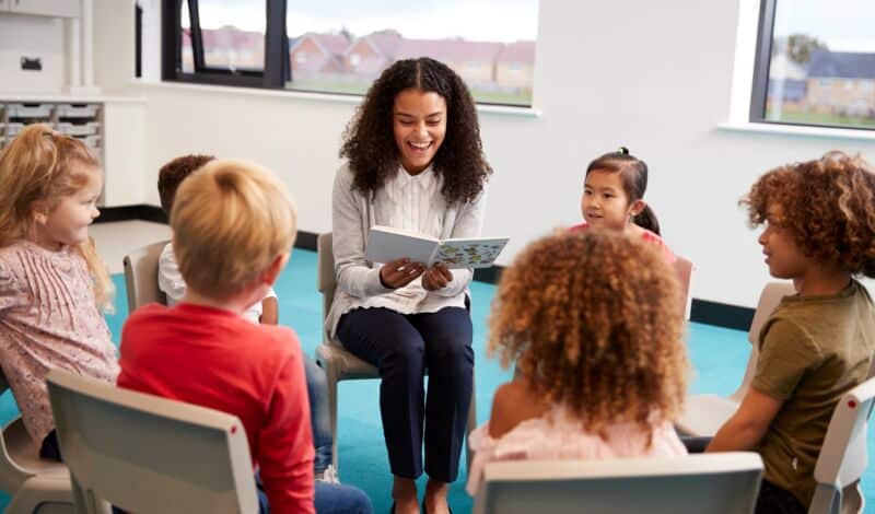 Lehrerin unterrichtet im Klassenzimmer vor Schülern im Kreis sitzend.