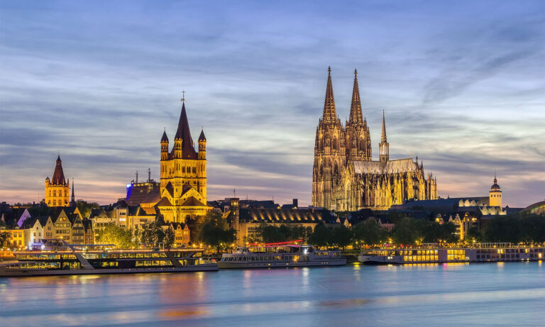 Panoramablick auf die Kölner Altstadt mit Dom und Groß St. Martin in der Abenddämmerung.