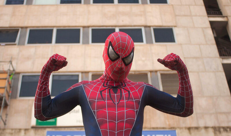 Ein Mann in einem Spiderman-Kostüm vor einem Hochhaus