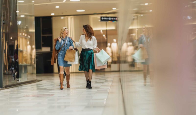 Zwei Frauen schlendern in einem Einkaufscenter