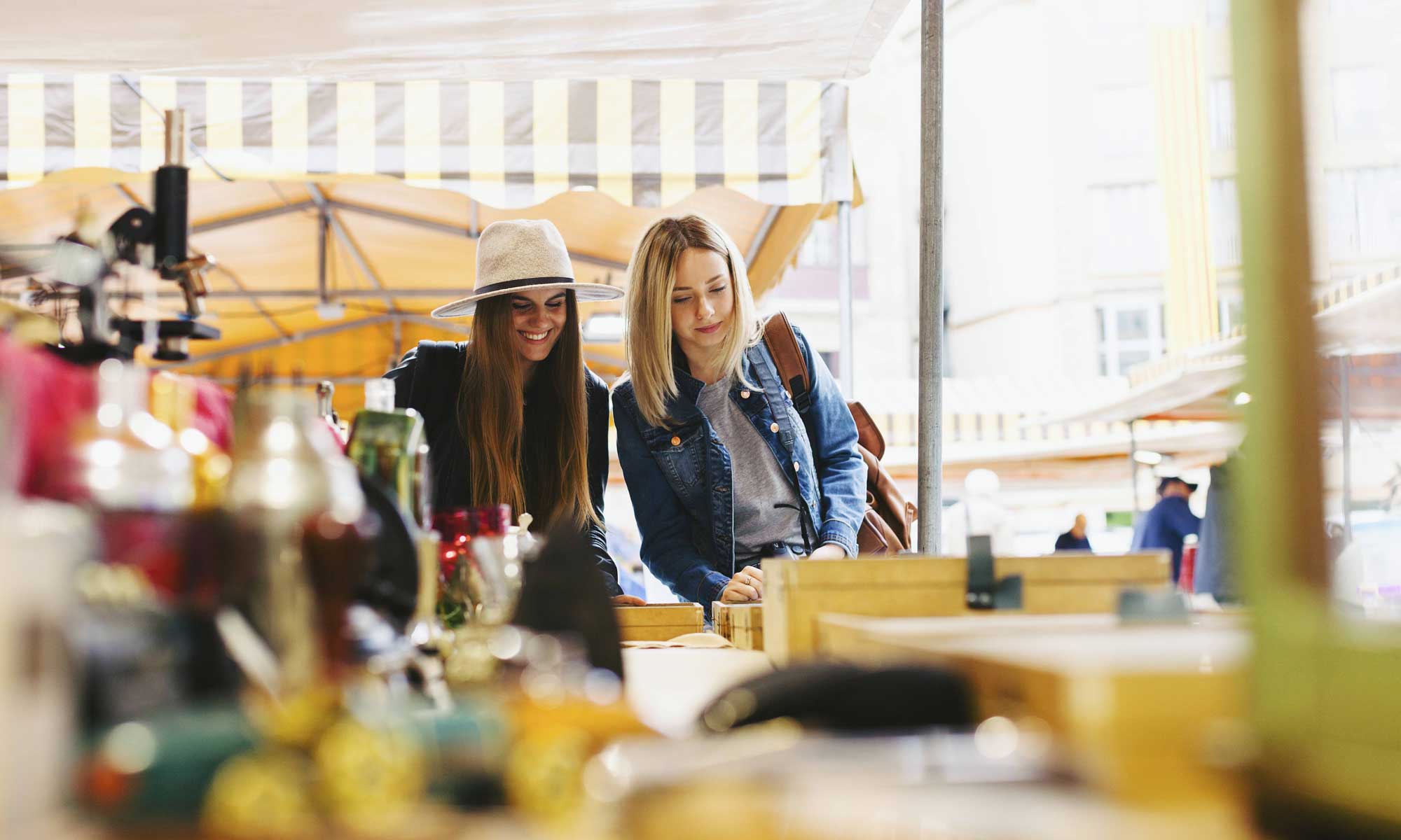 Zwei junge Frauen schlendern über einen Flohmarkt