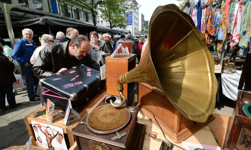 Ein Mann betrachtet die Auslage eines Händlers auf einem Antikmarkt.