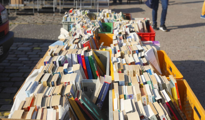 Das Bild zeigt aufgestapelte Bücher auf einem Flohmarkt.