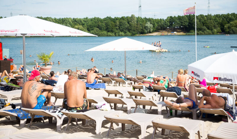 Badegäste auf Liegen im OMS Beach Club am Otto-Maigler-See