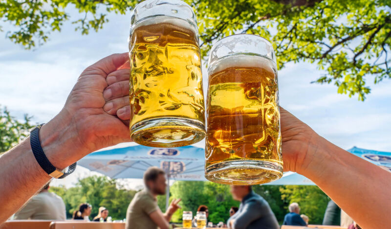 Zwei Männer stoßen mit einem großen Glaskrug Bier an.