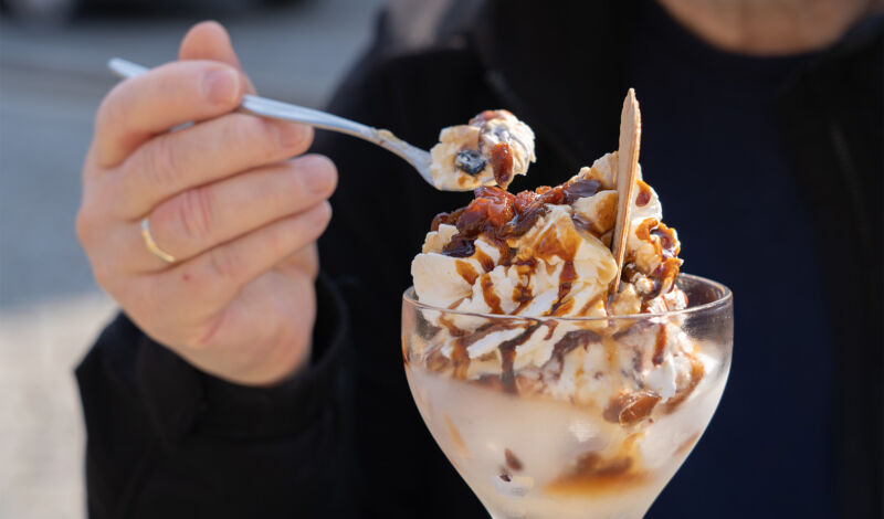 Ein Mann löffelt Eiscreme aus einem Eisbecher