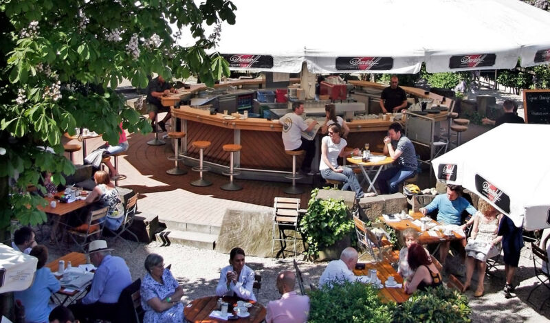 Besucher sitzen im Biergarten des Restaurants Maybach