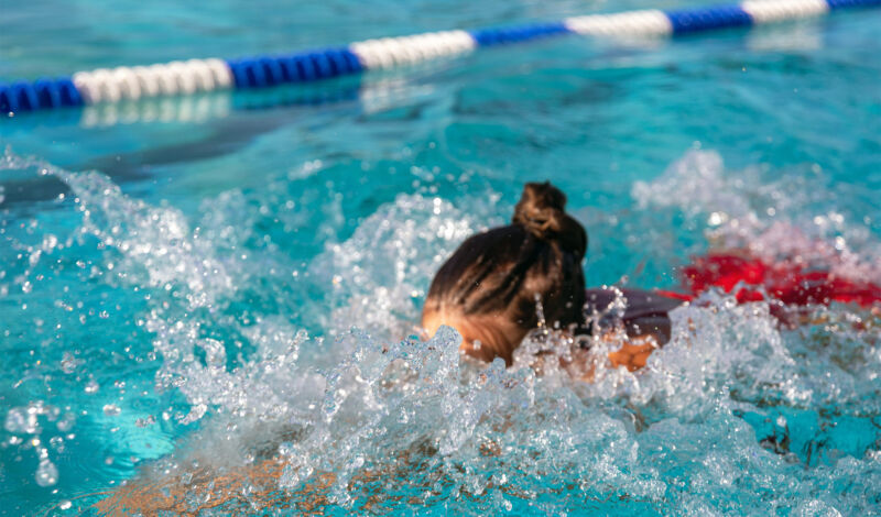 Eine junge Frau schwimmt auf einer Bahn in einem Freibad