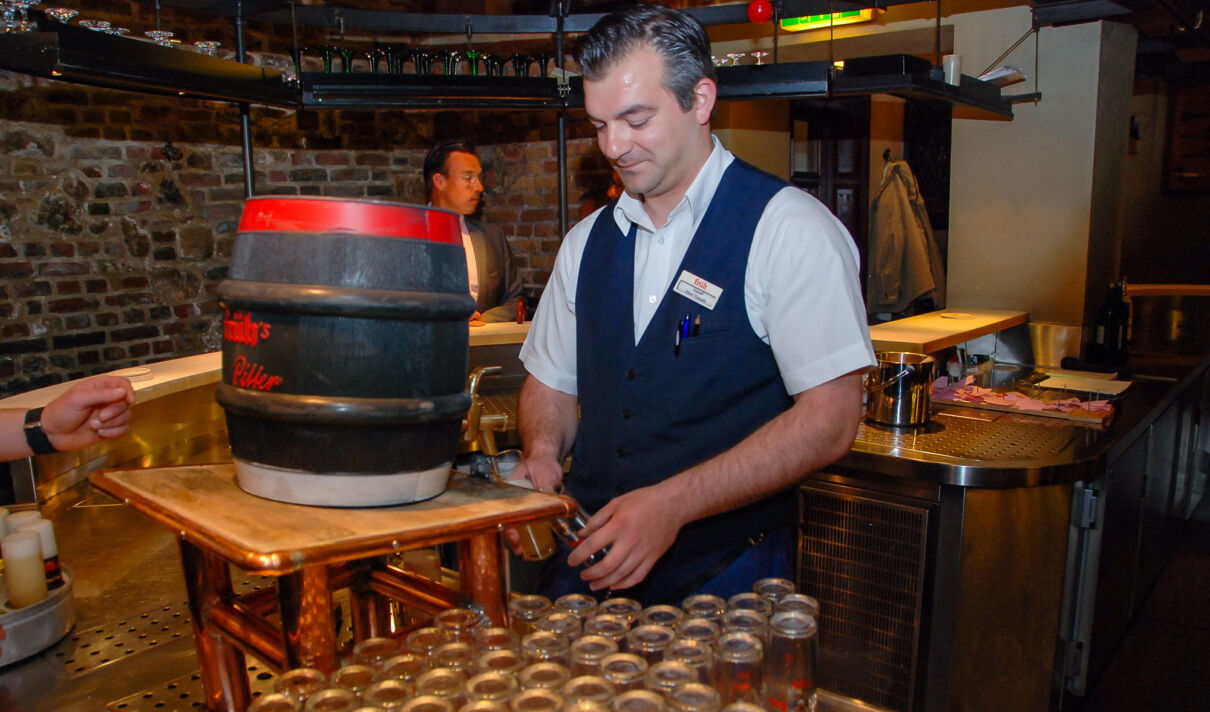 Ein Mitarbeiter eines Brauhauses zapft Bier aus einem Fass.