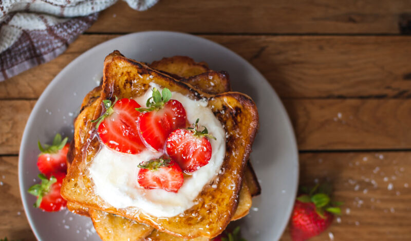 French Toast mit Erdbeeren auf einem grauen Teller auf einem Holztisch.