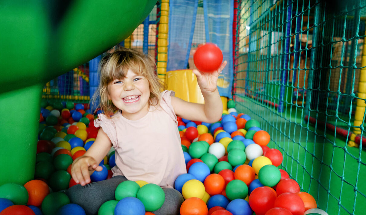 Ein Kind wirft in einem Indoor-Spielplatz einen Ball