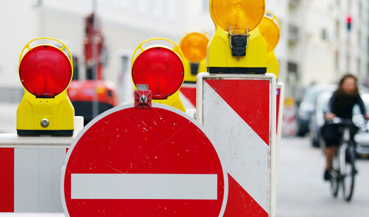 Warnbaken und ein Einbahnstraßenschild weisen auf eine gesperrte Straße hin.