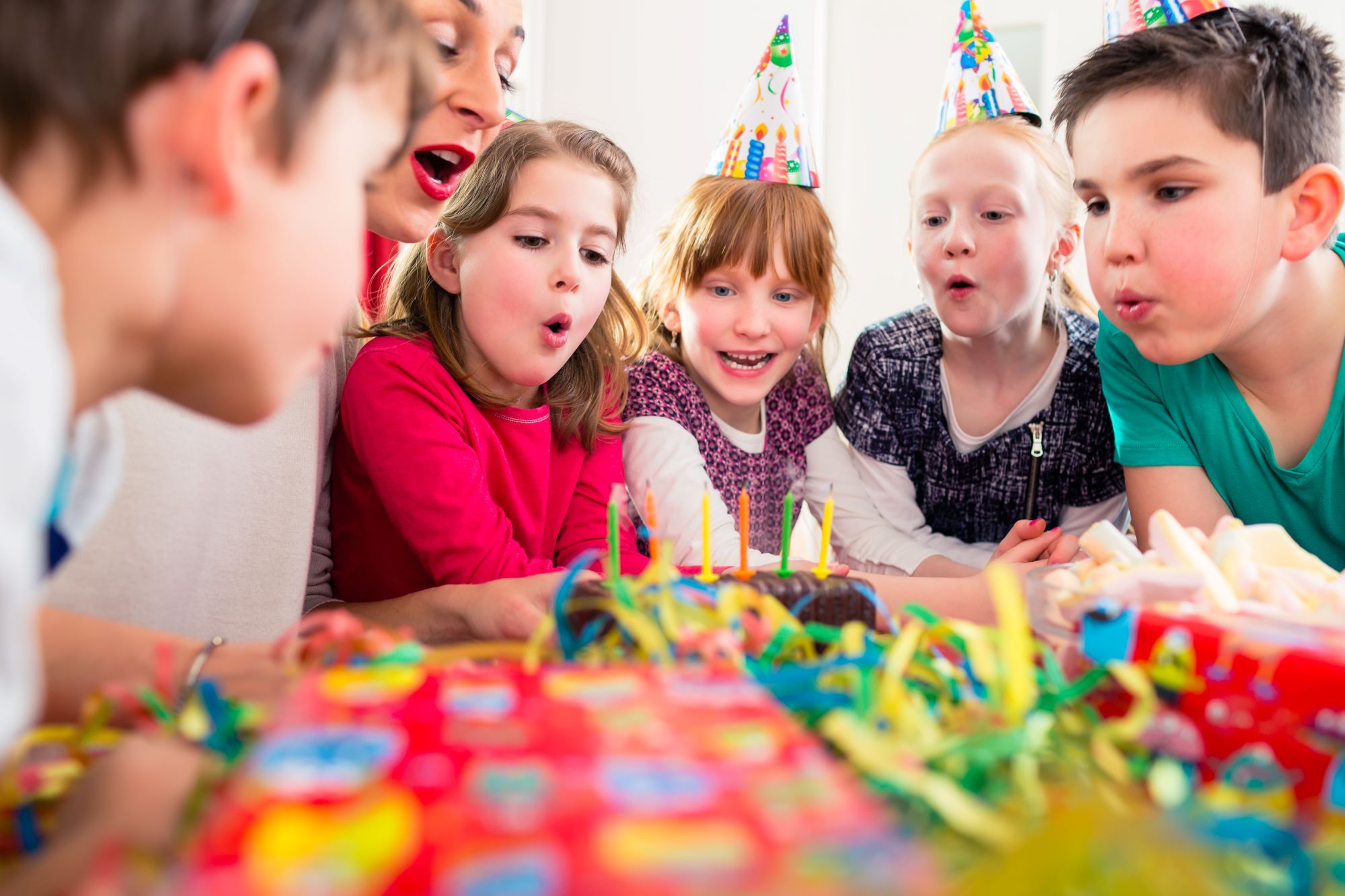 Kinder feiern einen Kindergeburtstag und blasen Kerzen aus