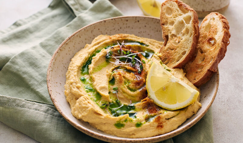 Hummus mit Öl, Zitrone und geröstetem Brot.