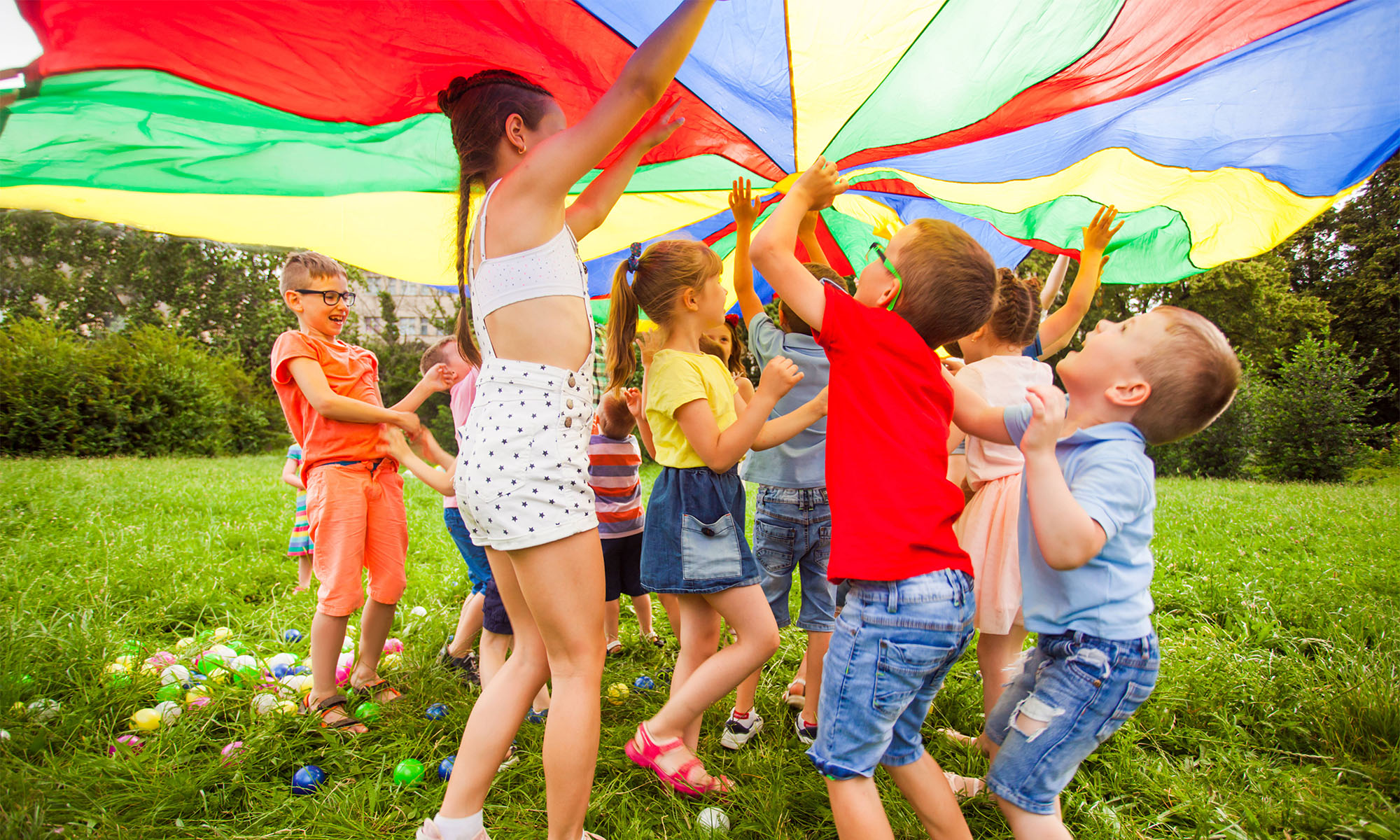 Das Bild zeigt Kinder, die im Sommer auf einer Wiese toben