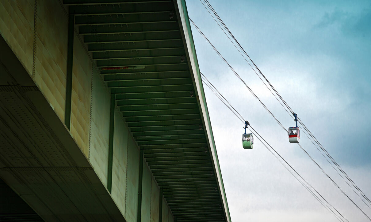 Blick von unten auf die Zoobrücke mit zwei Gondeln der Kölner Seilbahn im Hintergrund