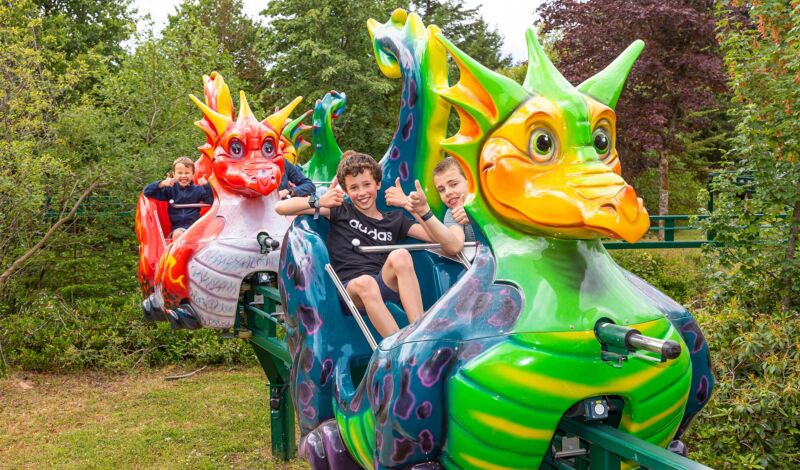 Kinder fahren auf der Drachenbahn im Freizeitpark.