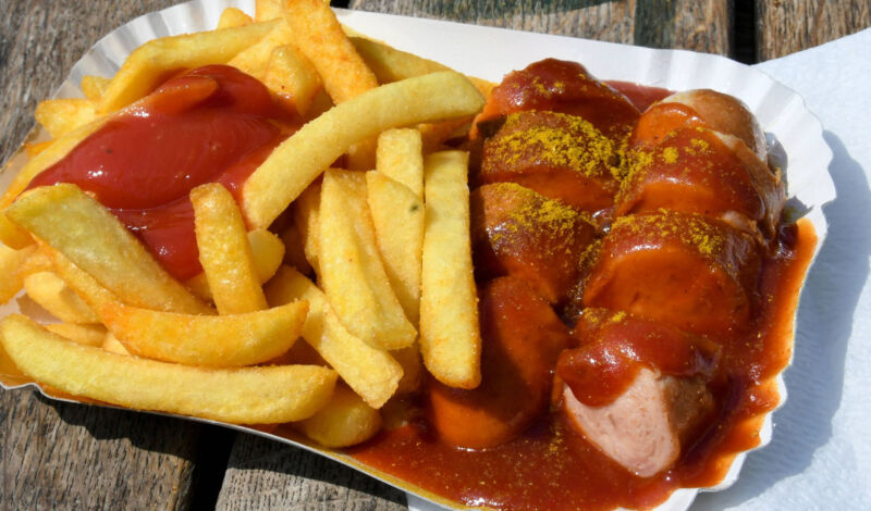 Currywurst und Pommes Frites in einer Pappschale