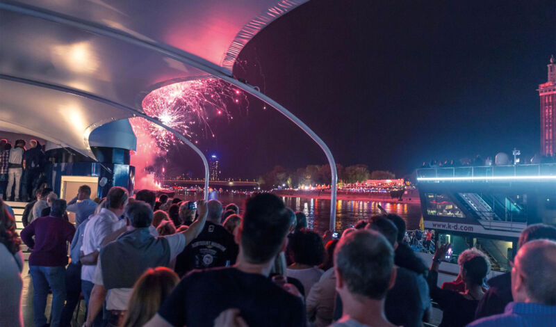 Gäste auf einem Rheinschiff beobachten das Feuerwerk an Silvester