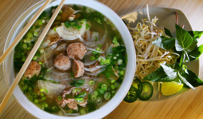 Eine Schale mit Suppe aus Asien, darauf Stäbchen sowie daneben eine Schale mit Sprossen