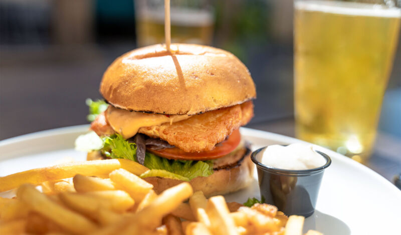 Ein Hamburger mit Pommes Frites und ein großes Glas Bier.