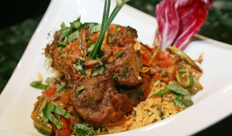 Das italienische Schmorgericht Ossobucco serviert mit kleinen Nudeln auf einem Teller.