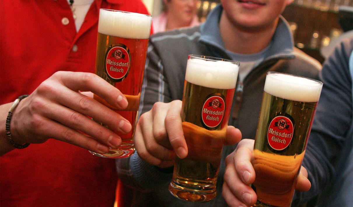 Männer stoßen mit drei Gläsern Kölsch von der Brauerei Reissdorf an