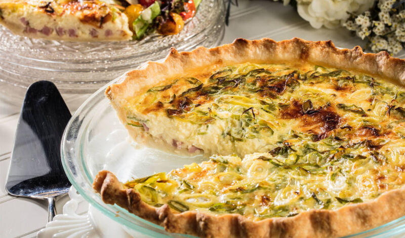 Eine klassische Quiche Lorraine, aus welcher ein Stück herausgeschnitten wurde