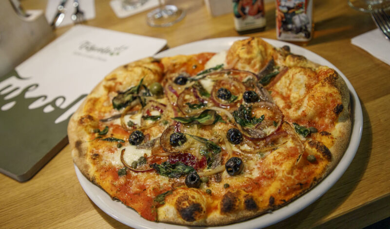 Eine Pizza mit Sardellen, Zwiebeln und Oliven im Restaurant