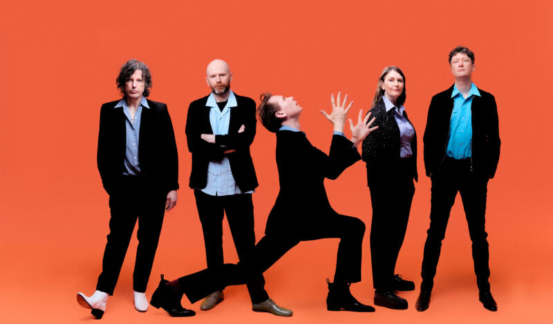 Die Mitglieder der britischen Band Franz Ferdinand vor einem orangefarbenen Hntergrund