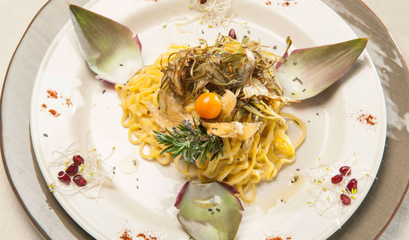 Pasta mit Pilzen und Artischocken garniert auf einem Porzellanteller