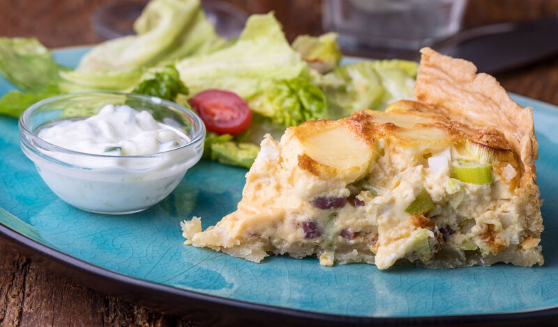 Ein Stück einer Quiche mit Quark und Salat auf einem blauen Teller