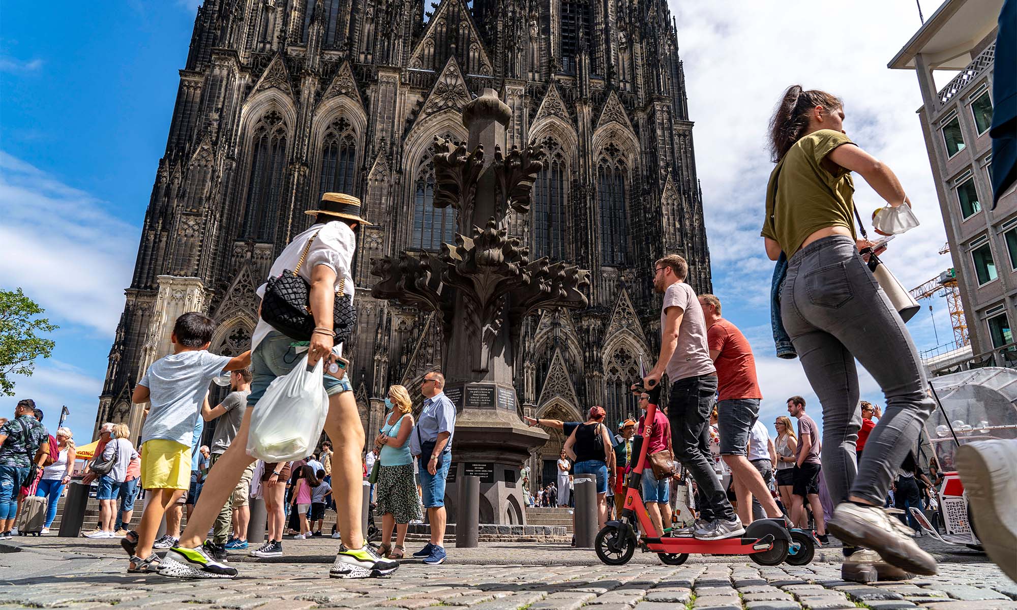 Passanten laufen auf Kopfsteinpflaster vor dem Kölner Dom