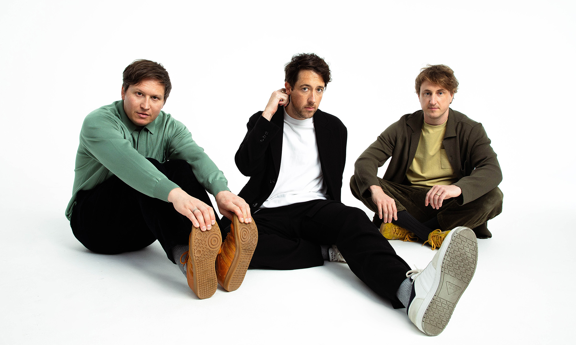 Die Musiker der britischen Alternativerockband The Wombats sitzen auf dem Boden